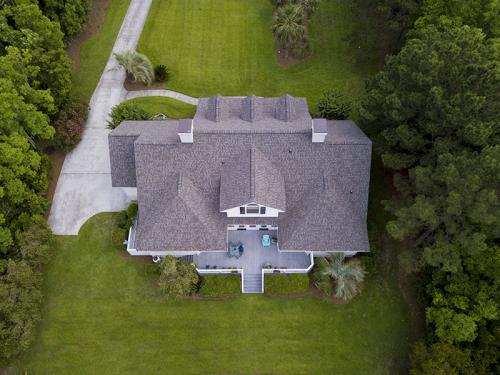 Aerial view of large home with new roof on beautiful property.